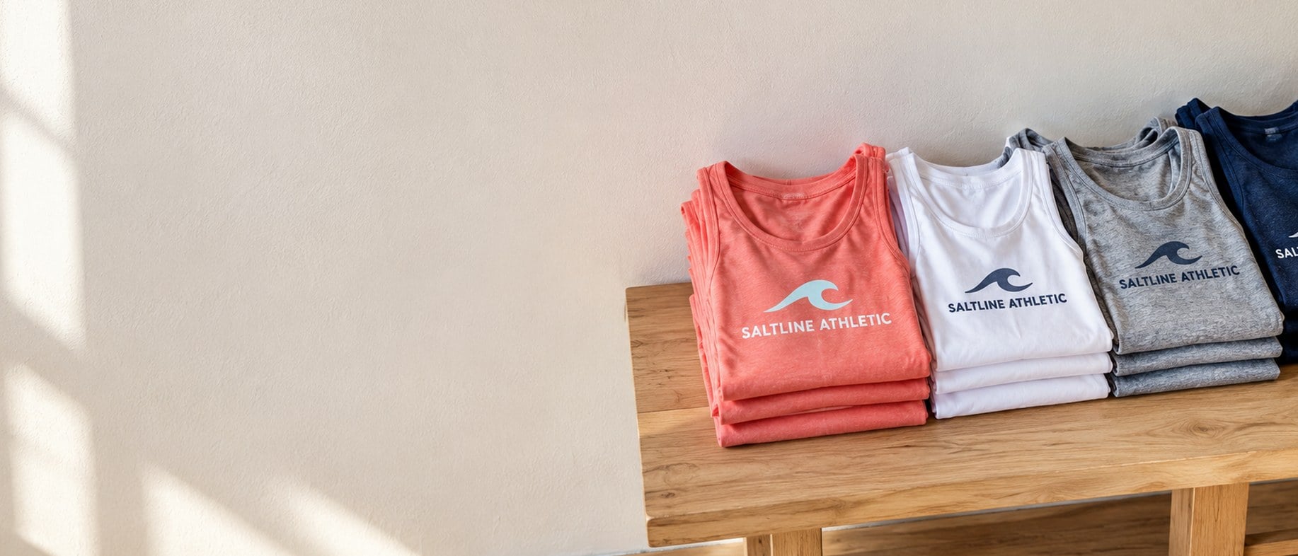 Custom printed tank tops folded in stacks on a wooden bench